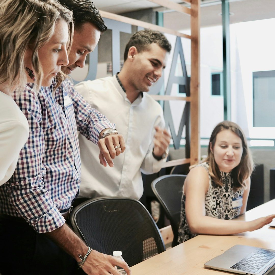 gestion ressources humaines Quatre personnes regardent un ordinateur portable et échangent des idées en réunion.