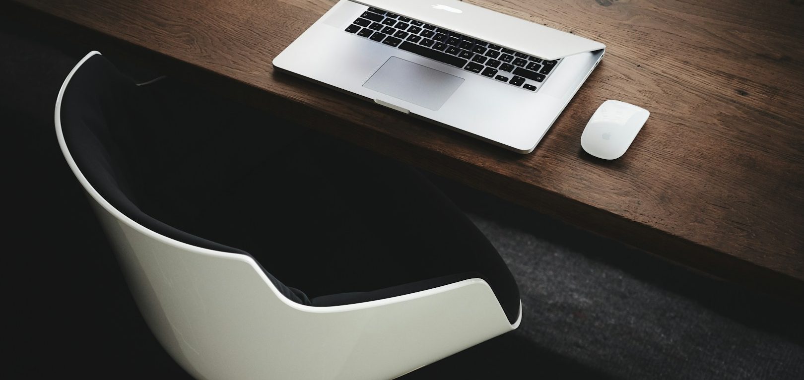 Le Carrefour Numérique Bureau en bois avec un ordinateur portable et une souris sur une chaise moderne.