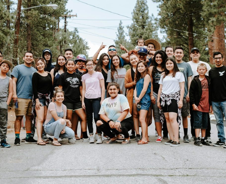 public Groupe de jeunes souriants en plein air, entouré d'arbres, sur une route.